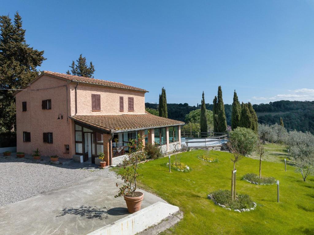 une maison avec une grande cour arborée en arrière-plan dans l'établissement Villa Cristina, à Riparbella
