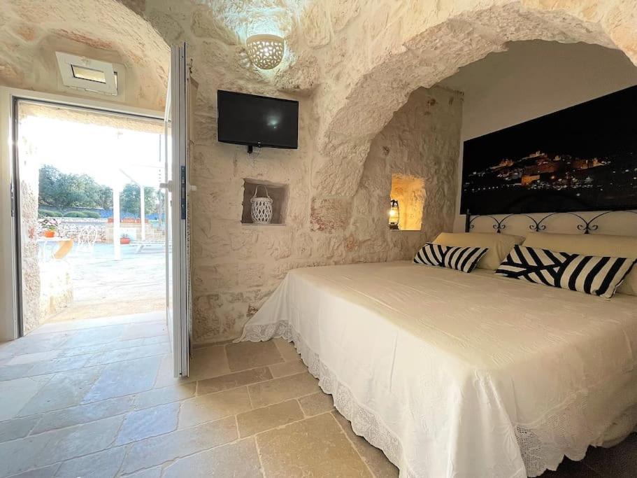 une chambre avec un lit et une télévision au mur dans l'établissement Oasi del Trullo, à Ostuni