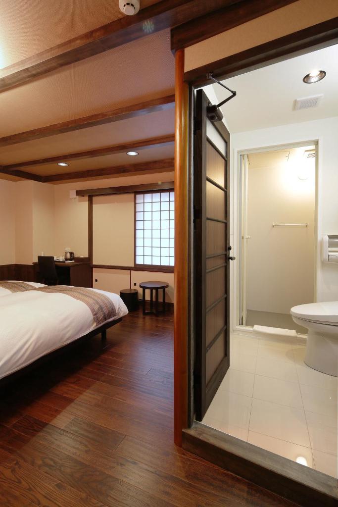 une chambre avec un lit et une salle de bain avec un lavabo dans l'établissement Kyomachiya Ryokan Sakura Urushitei, à Kyoto
