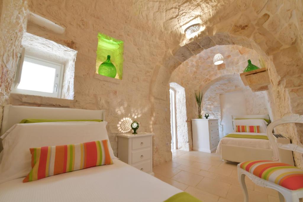 une chambre avec un lit blanc et un mur en pierre dans l'établissement Trulli Santa Croce - Luxury Holiday -, à Locorotondo
