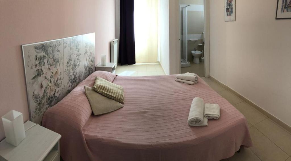 - une chambre avec un lit rose et des serviettes dans l'établissement Villa MiraScopello, à Castellammare del Golfo