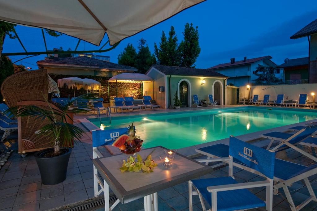 - une piscine avec des chaises et une table en face dans l'établissement Hotel Gabriella, à Rimini