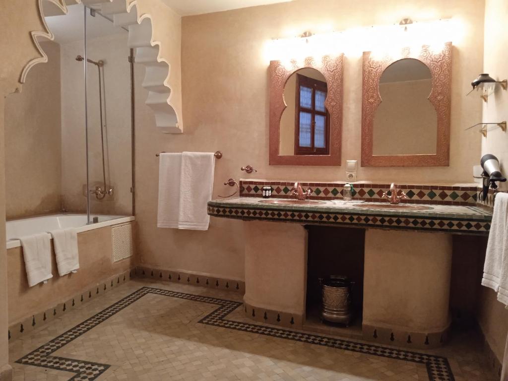 une salle de bain avec une baignoire, un lavabo et un miroir dans l'établissement Riad Meyssane Fès, à Fès