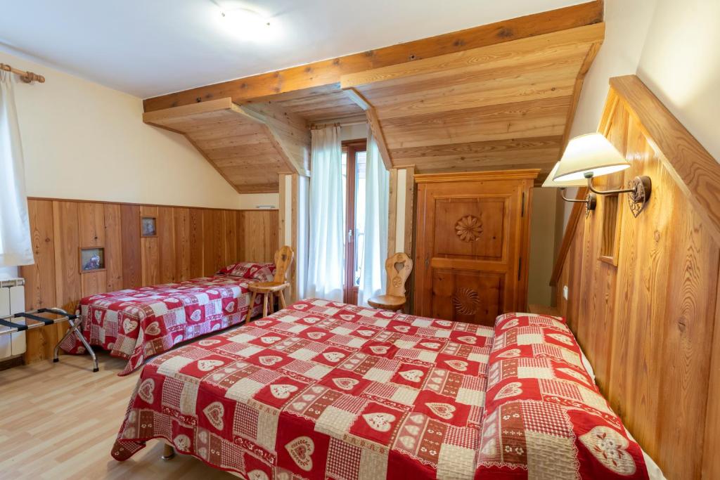 une chambre avec deux lits dans une pièce avec des plafonds en bois dans l'établissement Logis Hôtel Spa la Cascade, à Ceillac