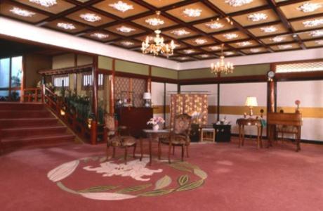 une grande chambre avec des chaises, une table et des escaliers dans l'établissement Kurhaus Ishibashi Ryokan, à Shimoda
