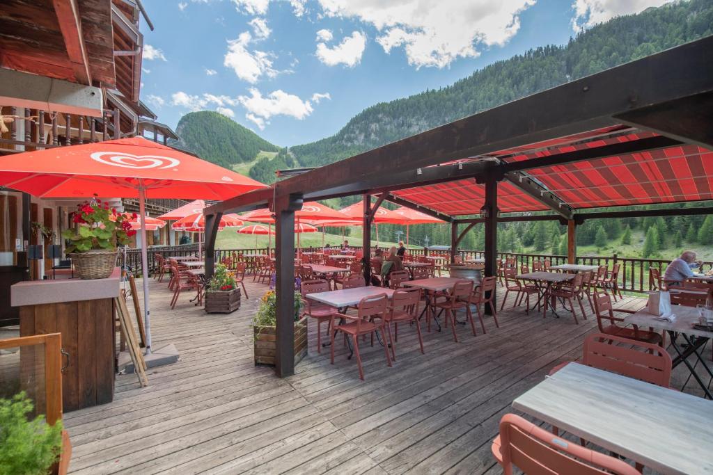 une terrasse en bois avec des tables, des chaises et des parasols dans l'établissement Logis Hôtel Spa la Cascade, à Ceillac