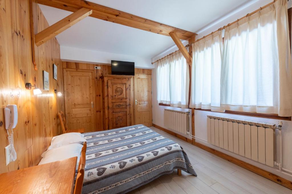 une chambre avec un lit dans une pièce aux murs en bois dans l'établissement Logis Hôtel Spa la Cascade, à Ceillac