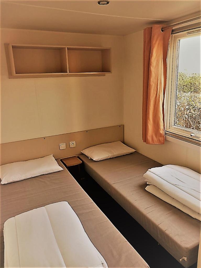 deux lits dans une chambre avec une fenêtre dans l'établissement MOBIL HOME Tendance Tout Confort - FUNPASS non included, à Gastes