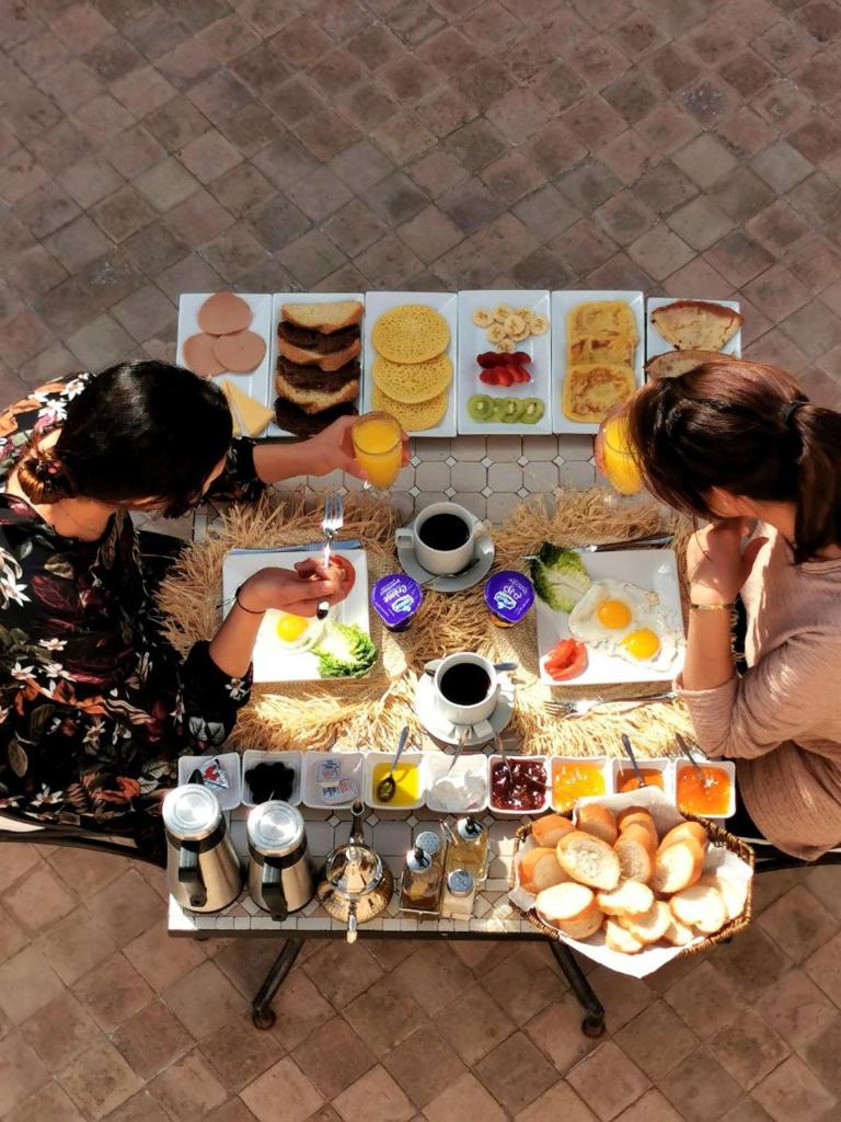 Deux femmes assises à une table avec de la nourriture dans l'établissement Riad Bijoux, à Marrakech