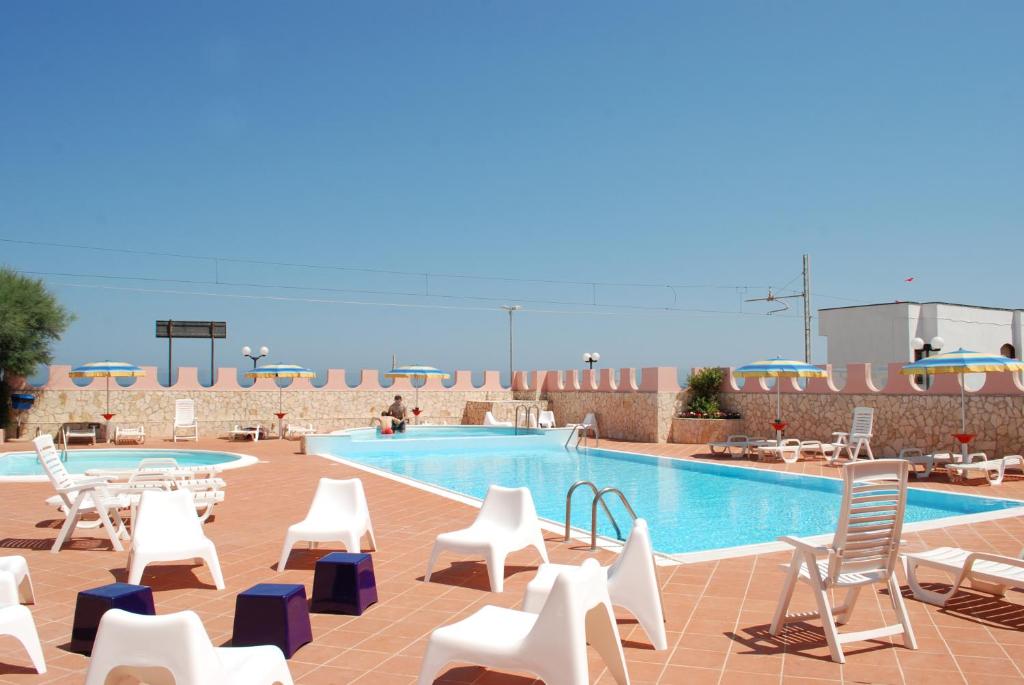 - une piscine avec des chaises blanches dans l'établissement HOTEL SOLE, à San Menaio