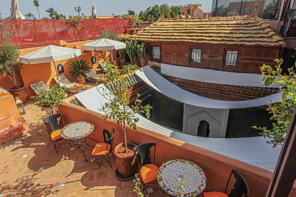 un patio extérieur avec tables et chaises et un bâtiment dans l'établissement Riad Melhoun & Spa, à Marrakech
