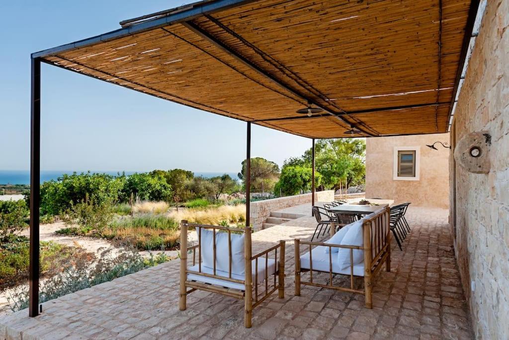 une terrasse avec un toit en bois, des chaises et une table dans l'établissement Casale Donna Costanza, à Scicli