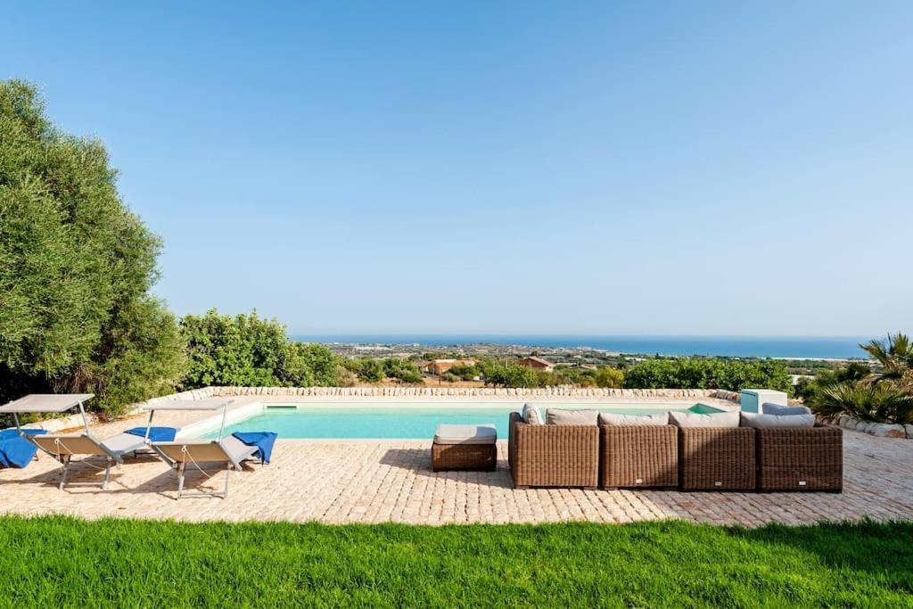 - une piscine avec des chaises et un canapé à côté dans l'établissement Casale Donna Costanza, à Scicli