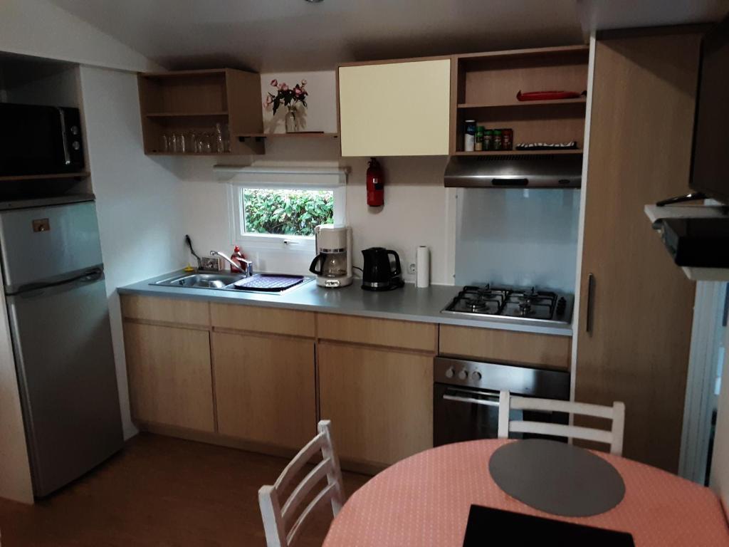 Il comprend une petite cuisine équipée d'une table, d'un évier et d'une cuisinière. dans l'établissement mobil home 3chambres tout confort, à Gastes