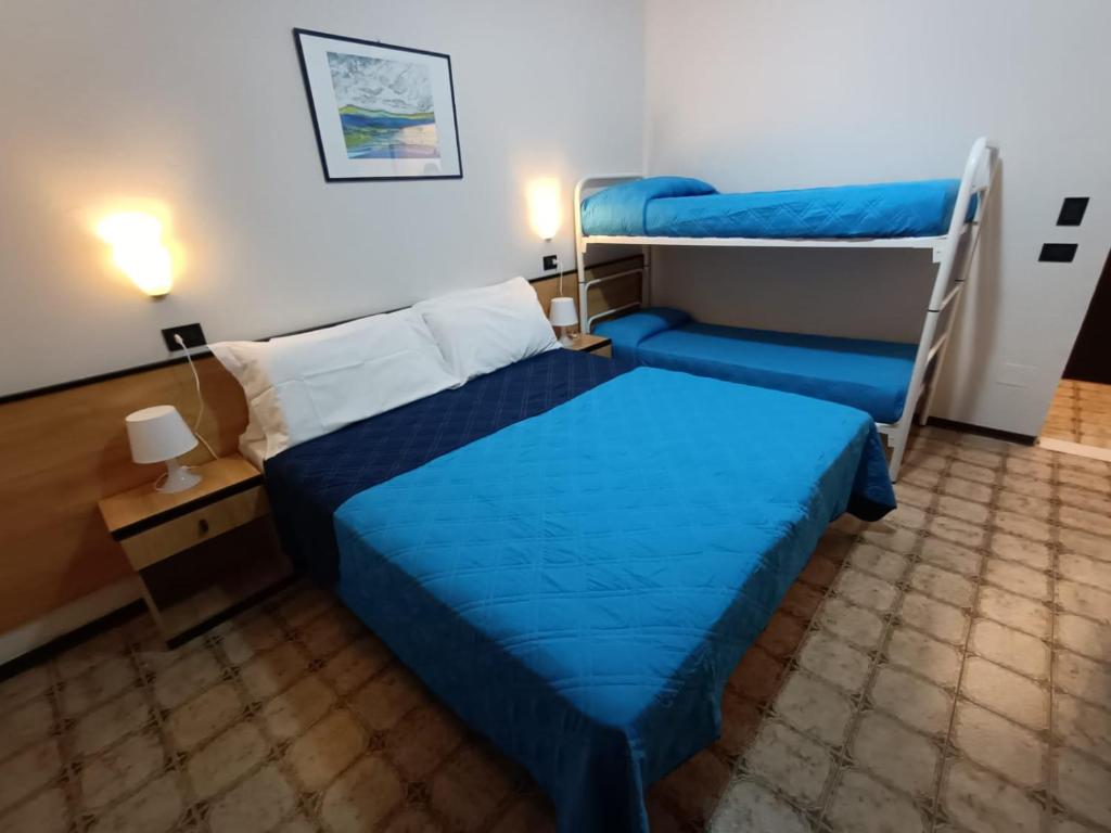 une chambre avec deux lits superposés et un lit bleu dans l'établissement Hotel La Torre, à Cervia