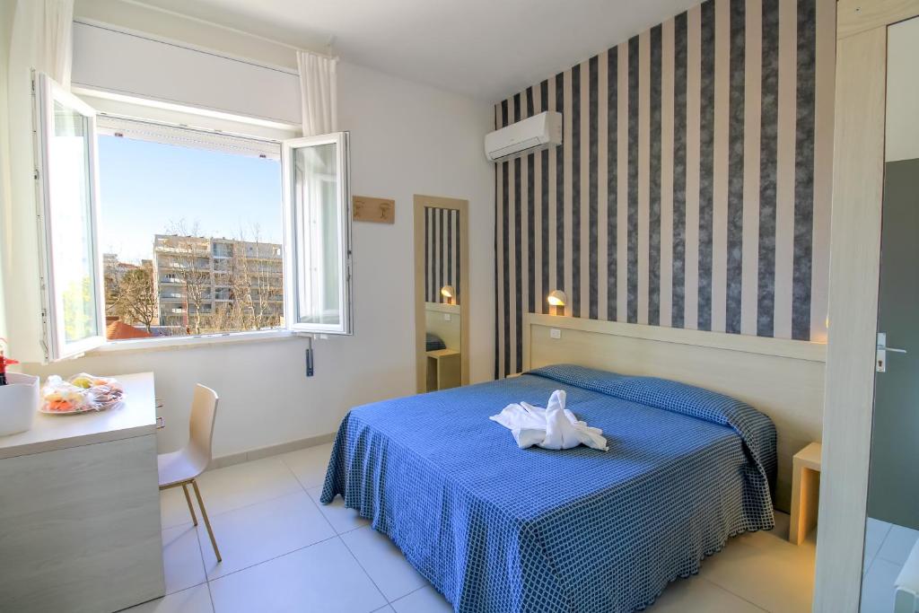 une chambre avec un lit bleu et une fenêtre dans l'établissement RESIDENZA ANNESSA Hotel Duca di Kent, à Cesenatico