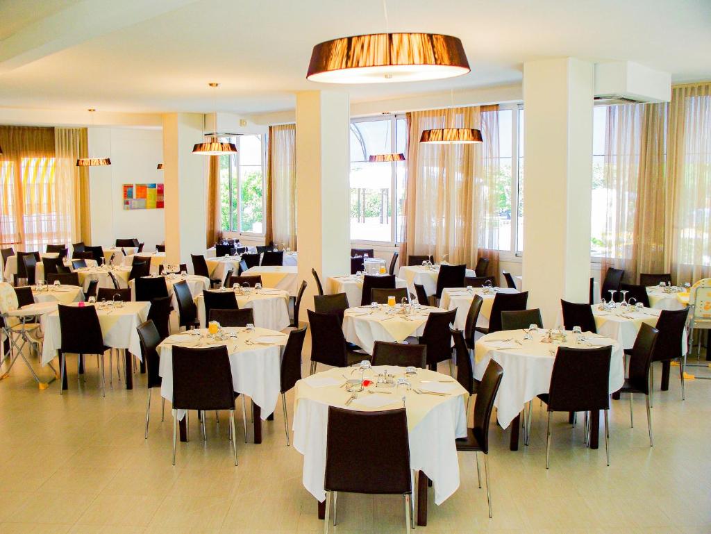 une salle à manger avec des tables blanches et des chaises noires dans l'établissement RESIDENZA ANNESSA Hotel Duca di Kent, à Cesenatico