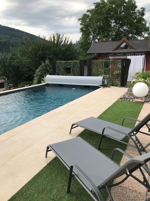 une piscine avec deux chaises et une table dans l'établissement Gîte des Renards, à La Broque