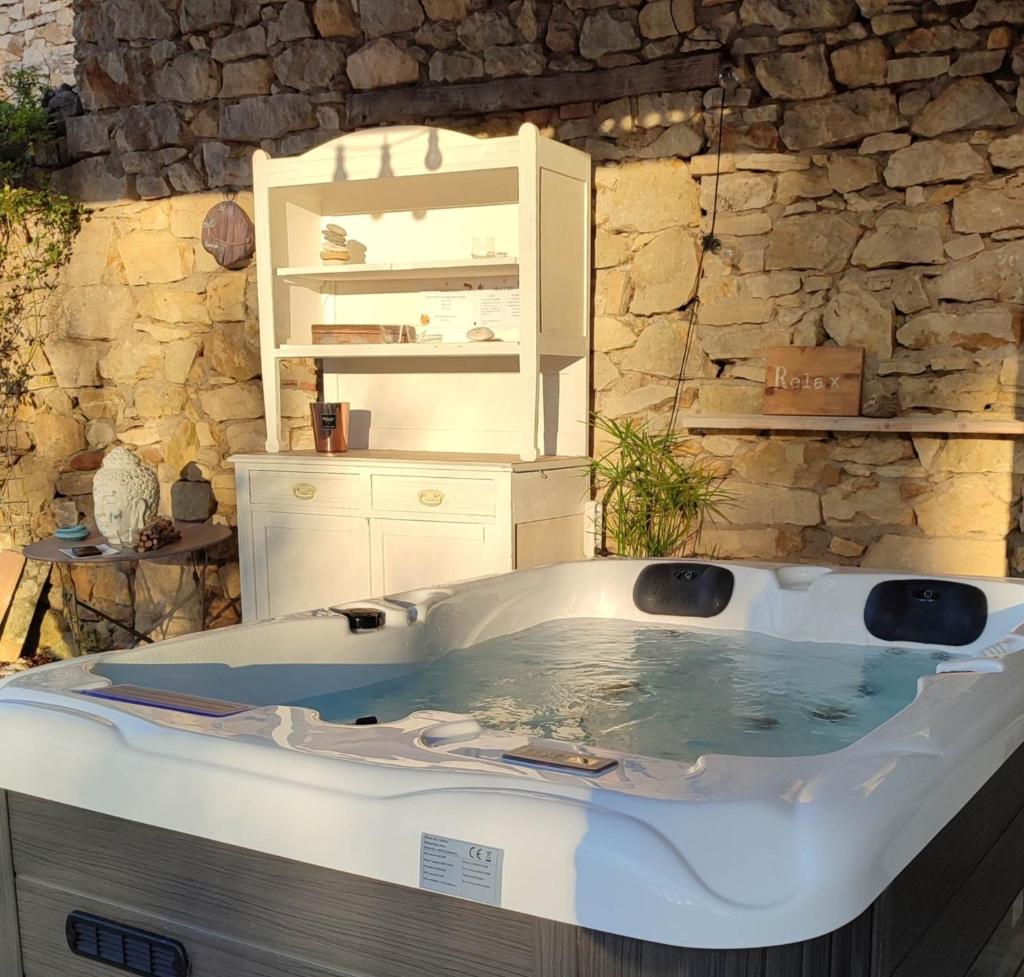 un bain à remous dans une pièce avec un mur en pierre dans l'établissement le gîte de Montagnac, à La Roque-sur-Cèze