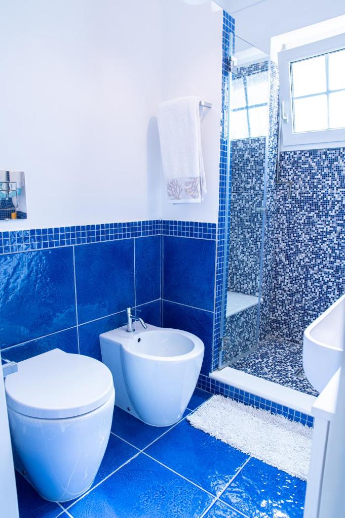 La salle de bains est pourvue de carrelage bleu, de toilettes et d'une douche. dans l'établissement Capri Villa Vittoria by Capri Property, à Anacapri
