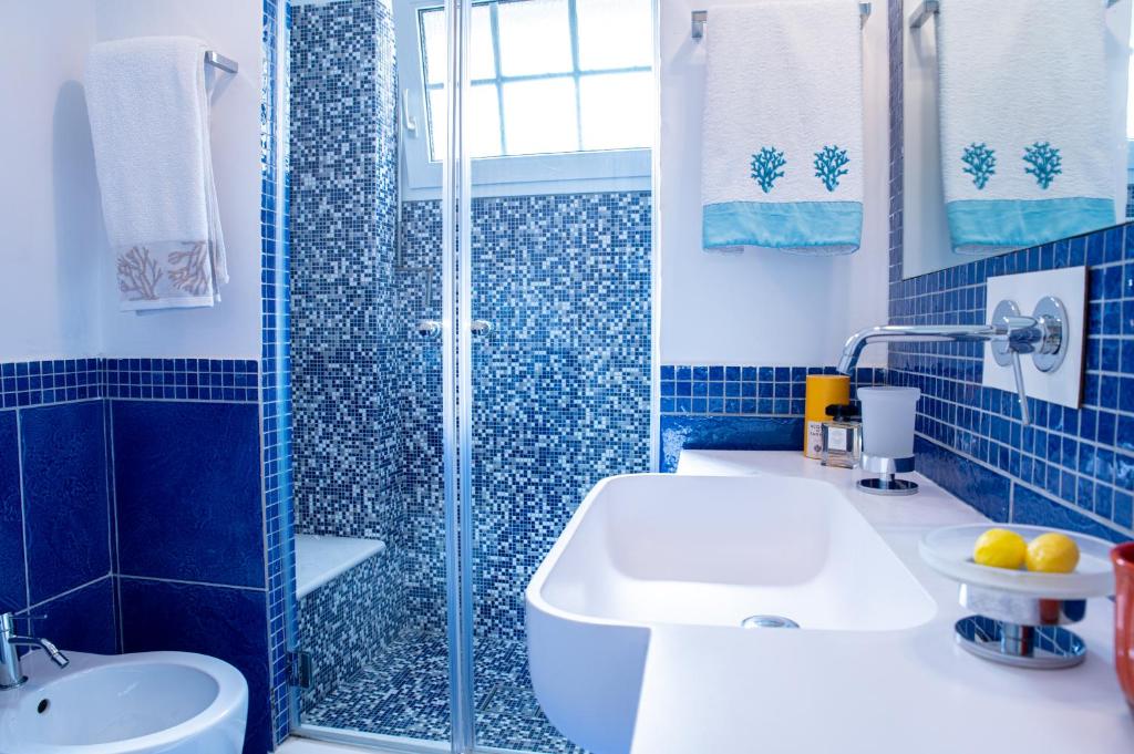 une salle de bain carrelée bleue avec un lavabo et une douche dans l'établissement Capri Villa Vittoria by Capri Property, à Anacapri