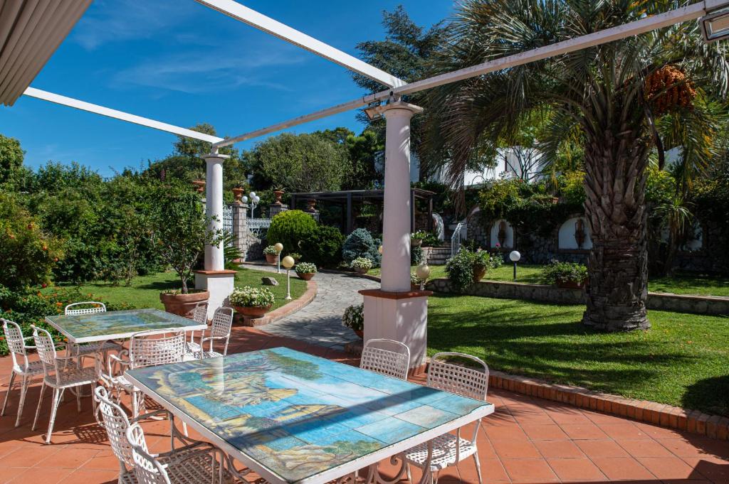 un patio avec une table, des chaises et des arbres dans l'établissement Capri Villa Vittoria by Capri Property, à Anacapri