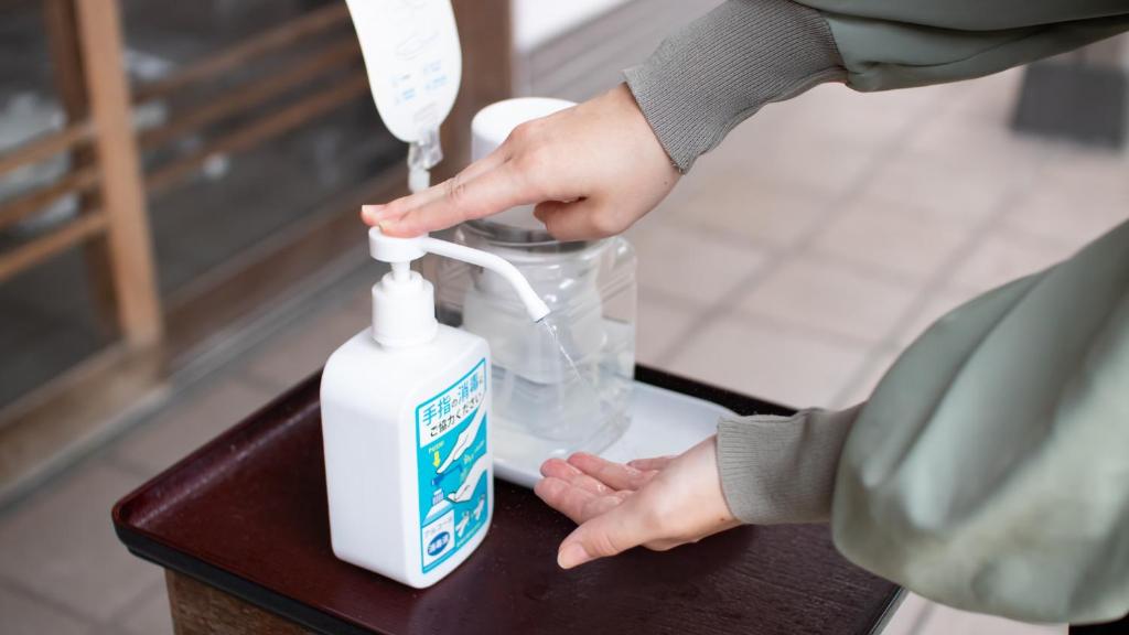 une personne tient une bouteille de désinfectant de la main sur une table dans l'établissement Tokiwa Bekkan, à Toyooka