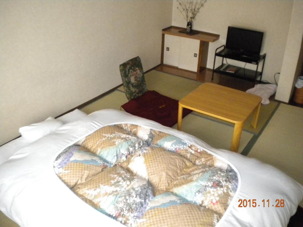 - une chambre avec un grand lit, une table dans l'établissement Mimatsuso Ryokan, à Asahikawa