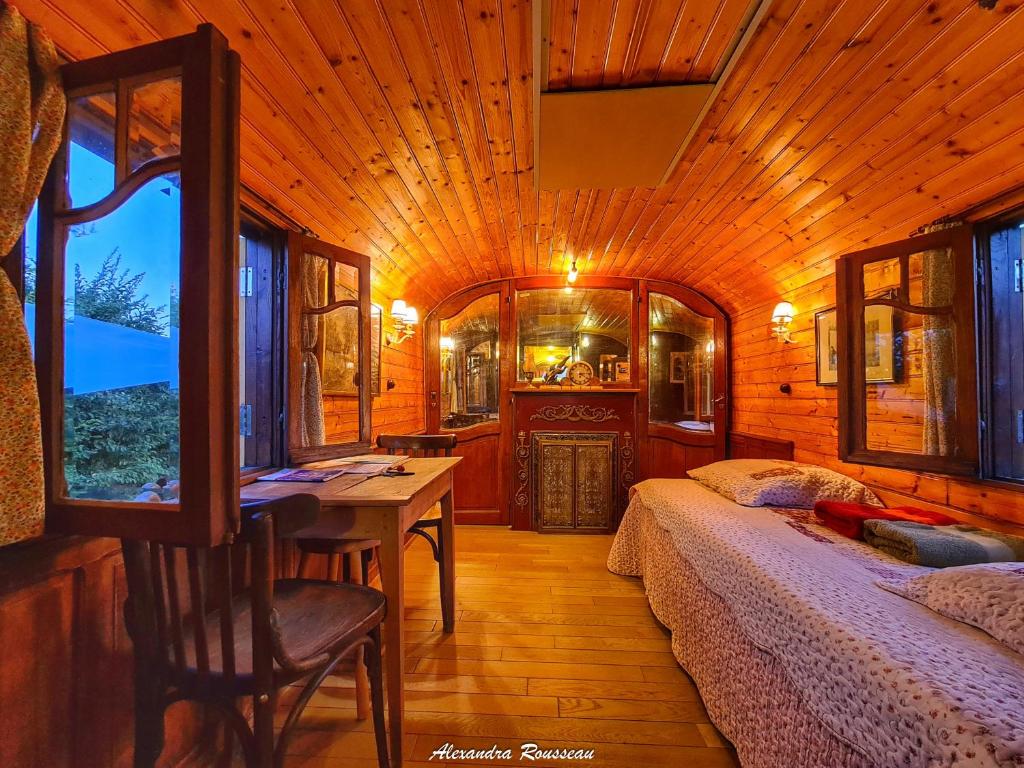 - une chambre avec 2 lits et une table dans une cabine dans l'établissement Manoir du Bois Joly - Roulotte Art Déco, à Margon