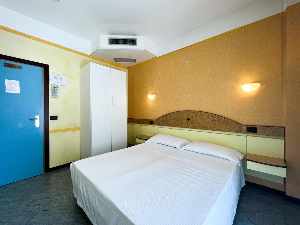 - une chambre avec un grand lit blanc et une porte bleue dans l'établissement Hotel Soleblu, à Rimini