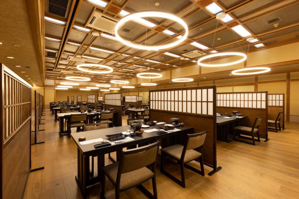 une salle à manger avec des tables, des chaises et des lumières dans l'établissement Shima Yamaguchikan, à Nakanojo