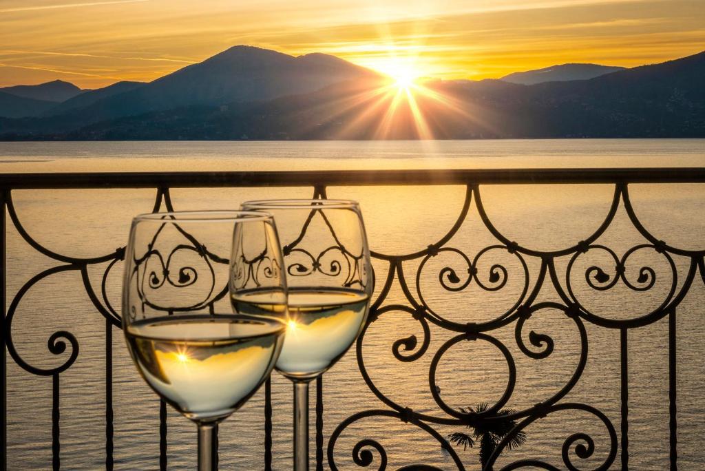 deux verres de vin blanc sur un balcon avec le coucher du soleil dans l'établissement Residence Casa e Vela, à Oggebbio