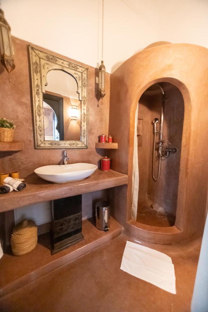 une salle de bain avec un lavabo et une douche avec un miroir dans l'établissement Riad Baba Ali, à Marrakech