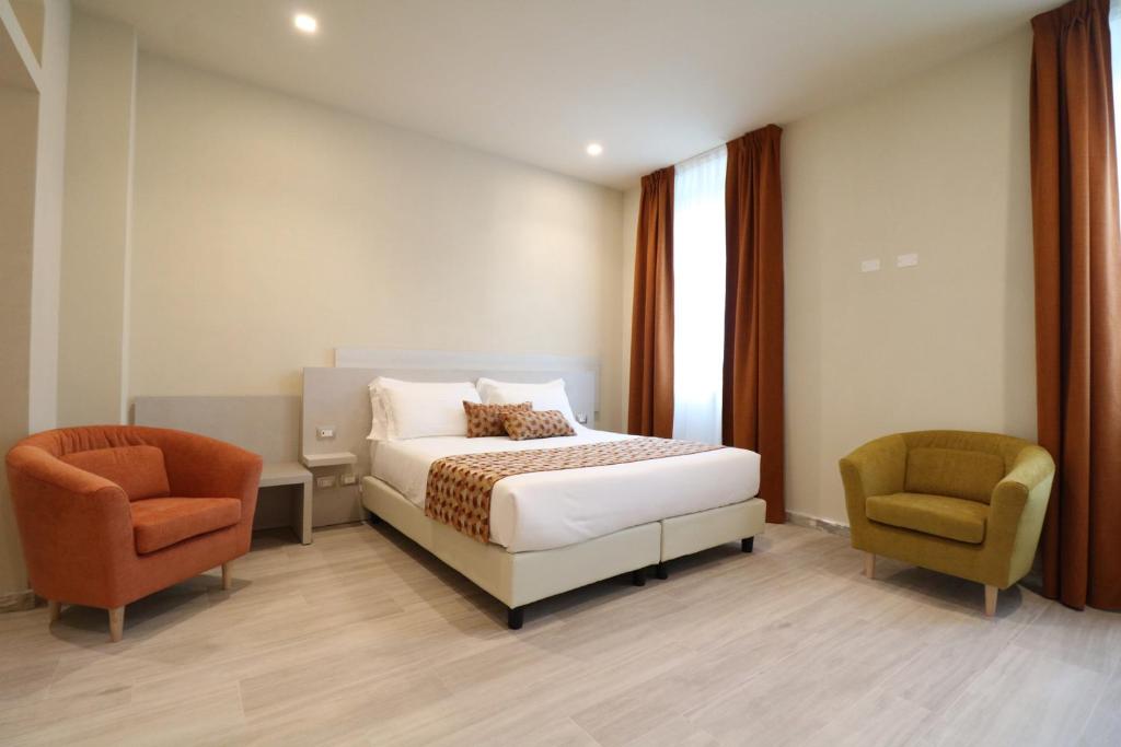 une chambre d'hôtel avec un lit et deux chaises dans l'établissement Doride Suites Boutique Hotel, à Marina di Carrara