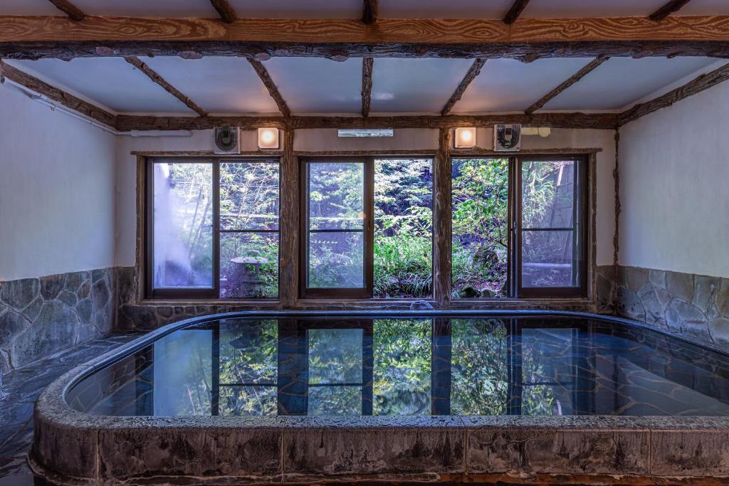 une piscine intérieure dans une maison avec des fenêtres dans l'établissement Ichinoyu Honkan, à Hakone