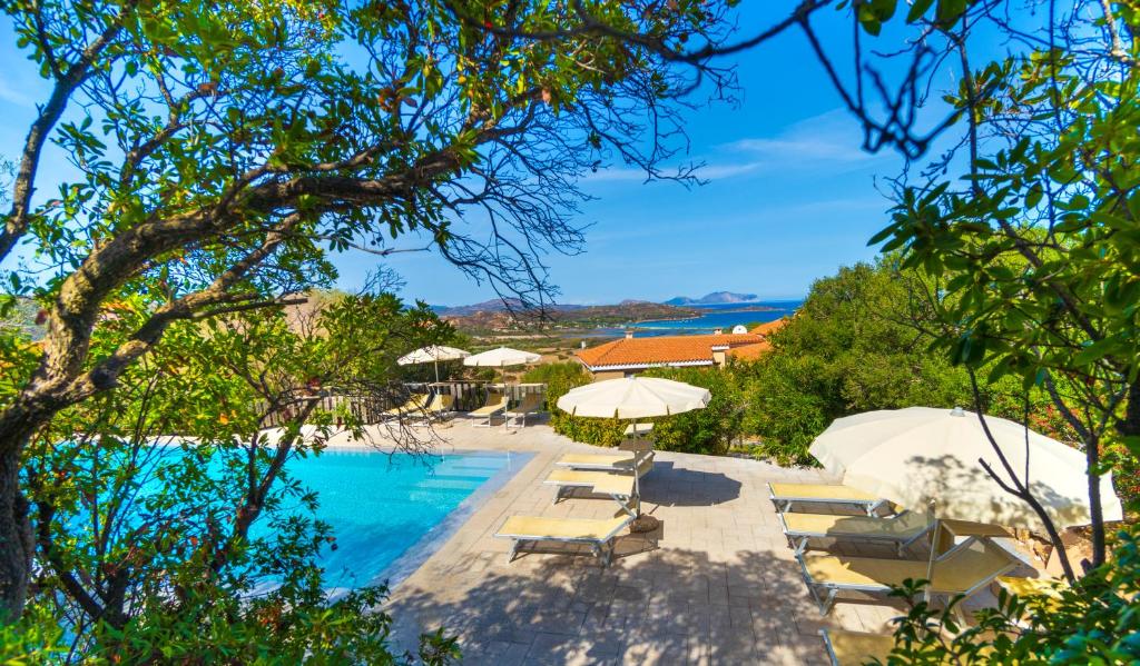 une piscine avec chaises longues et parasols dans l'établissement Residence Hotel Lu Nibareddu, à San Teodoro