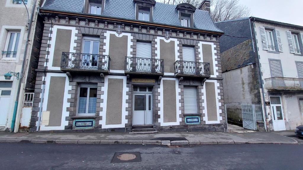un vieux bâtiment avec des finitions blanches et brunes dans une rue dans l'établissement Villa de la dore, à Le Mont-Dore