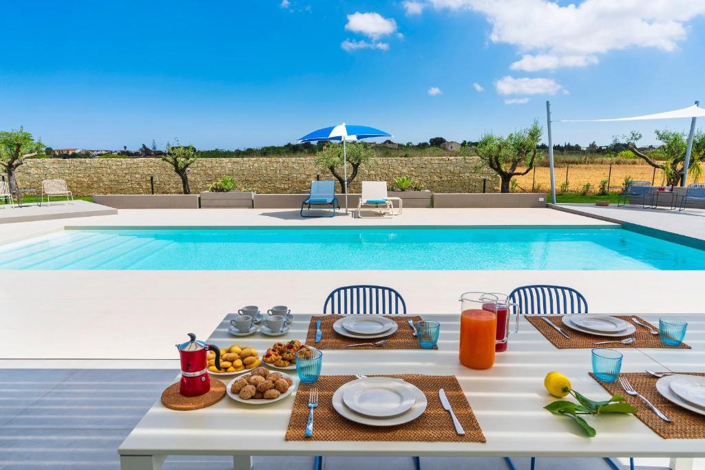 une table avec de la nourriture dessus à côté d'une piscine dans l'établissement Villa Mia, à Reitani