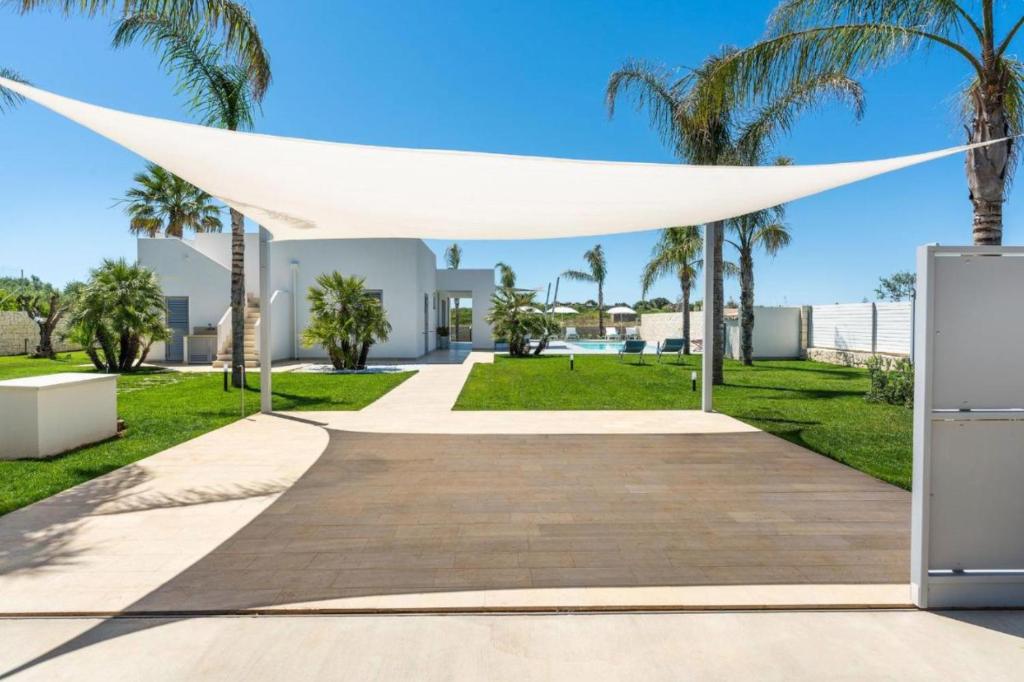 un auvent blanc sur une passerelle dans un parc planté de palmiers dans l'établissement Villa Nica, à Reitani