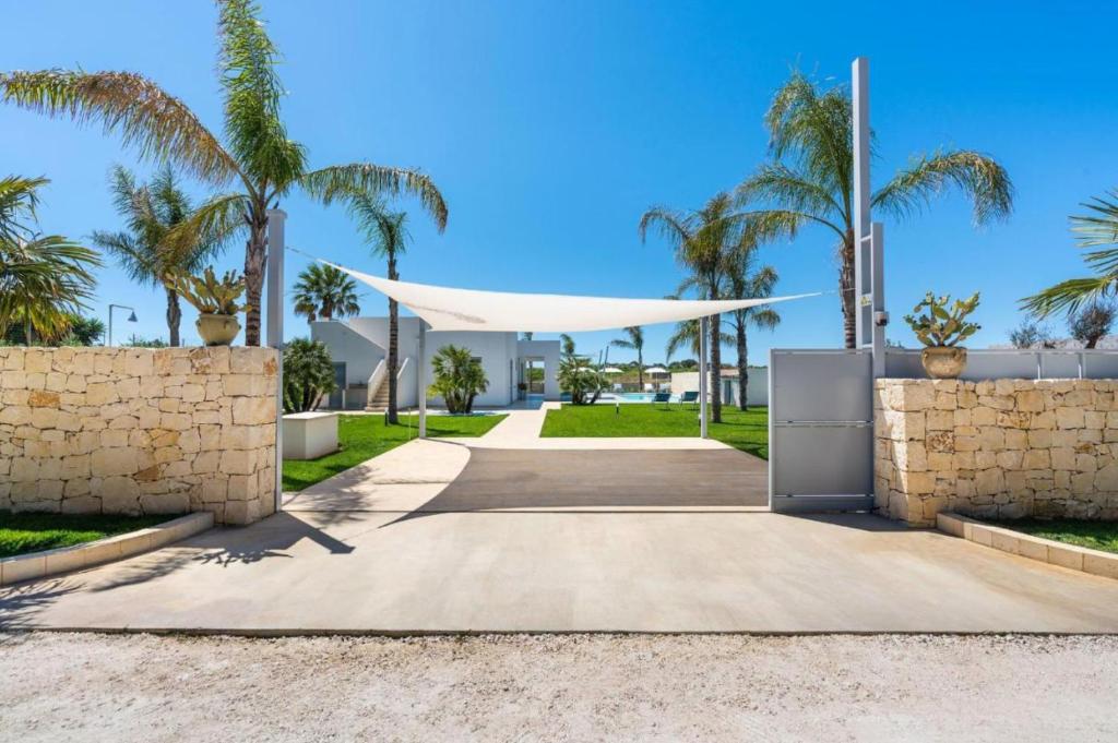 une allée en face d'une villa avec des palmiers dans l'établissement Villa Nica, à Reitani