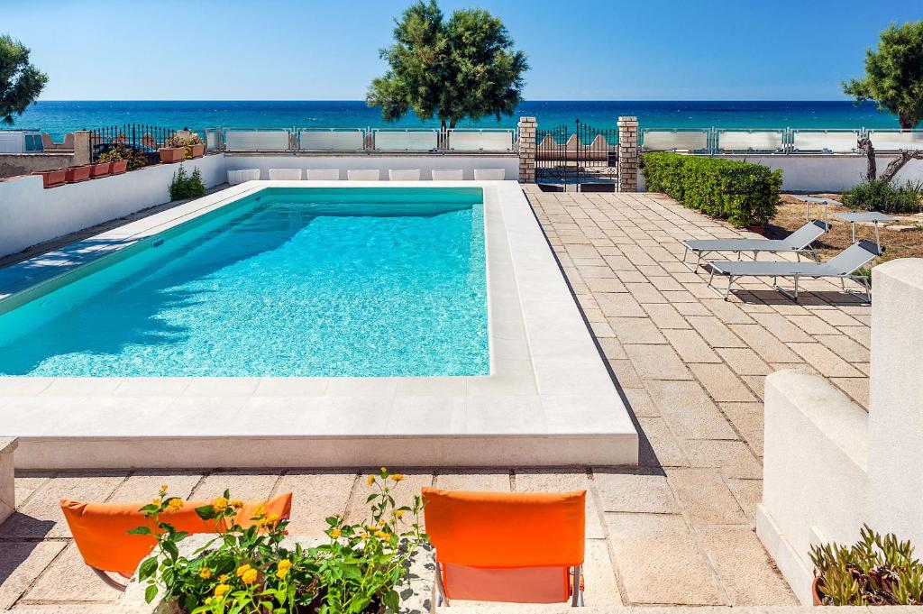- une piscine avec des chaises orangées et l'océan dans l'établissement Profumo di Mare, à Custonaci