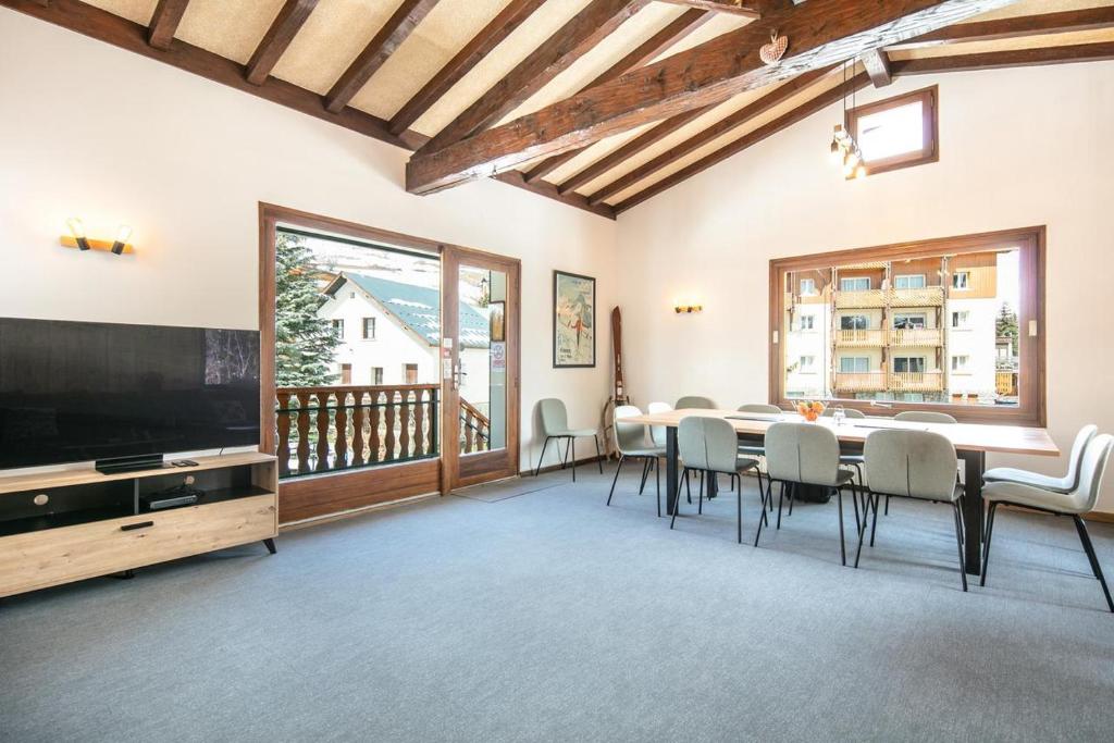 une salle à manger avec une table, des chaises et une télévision dans l'établissement Le Chalet, à Les Deux Alpes