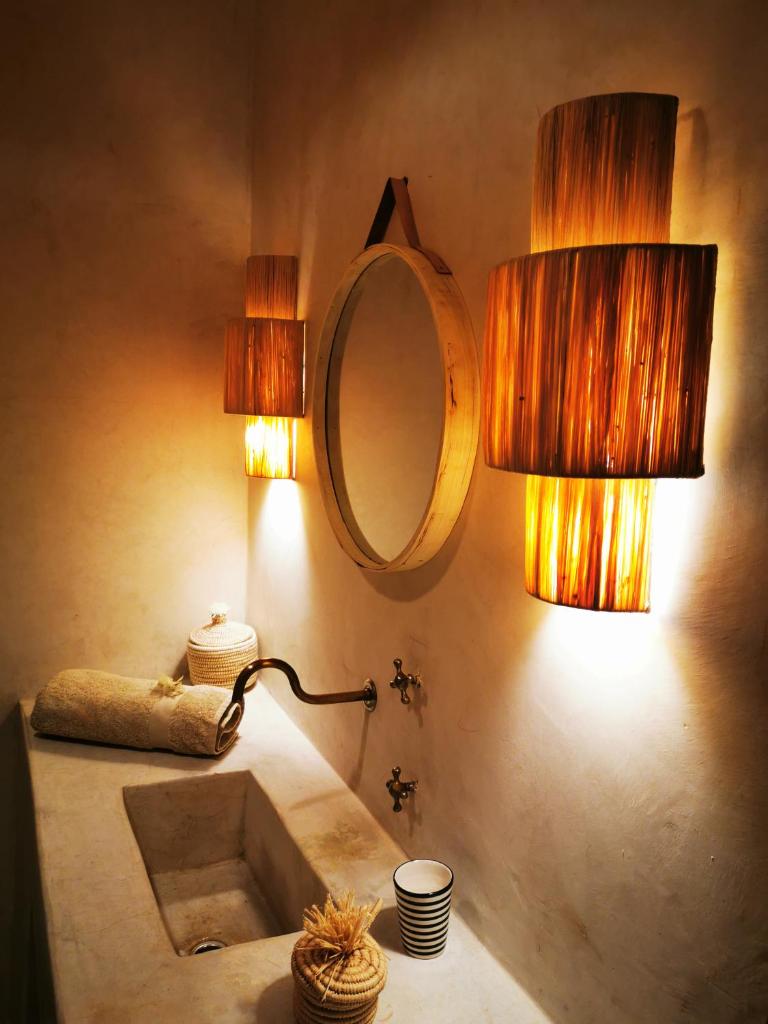 La salle de bains est pourvue d'un lavabo, de 2 lampes et d'un miroir. dans l'établissement Riad Bab aylen - Piscine Roof Top chauffée, à Marrakech