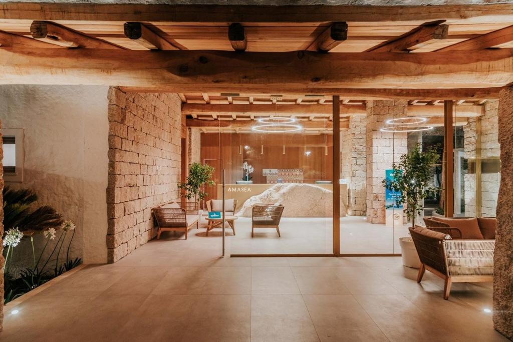 un hall d'entrée avec un mur de briques, des chaises et des tables dans l'établissement AMASEA Resort, à San Teodoro