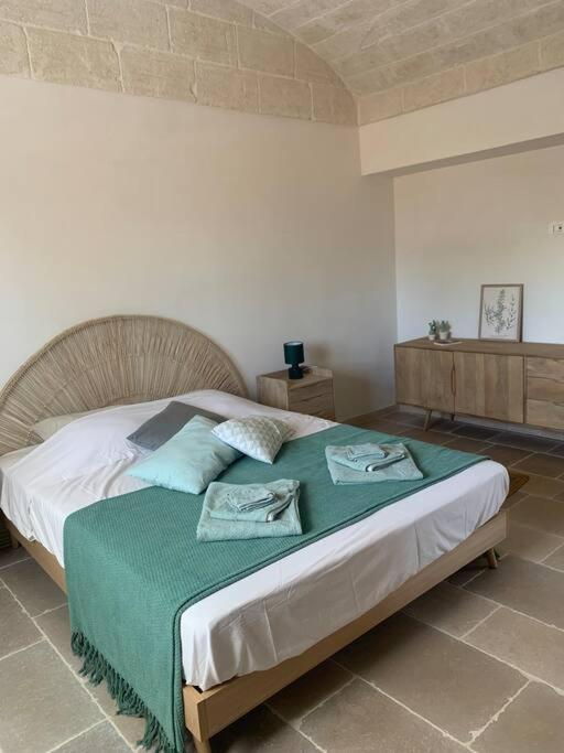 une chambre avec un grand lit avec une couverture verte dans l'établissement Trullo FICOLI, à Ostuni