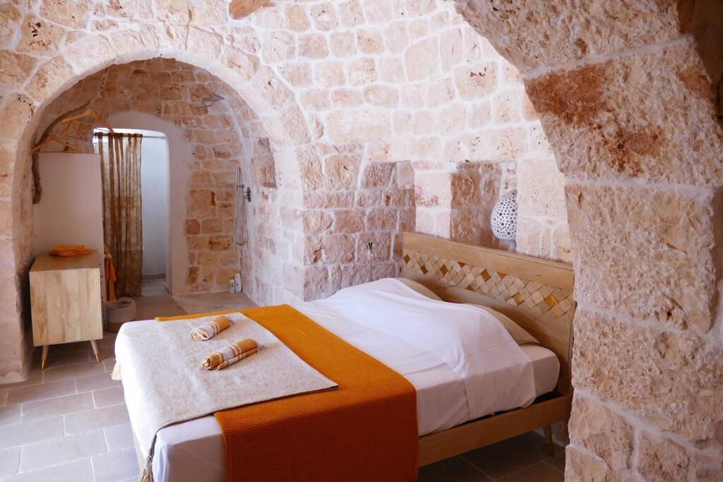 une chambre avec un lit dans un mur de pierre dans l'établissement Trullo FICOLI, à Ostuni
