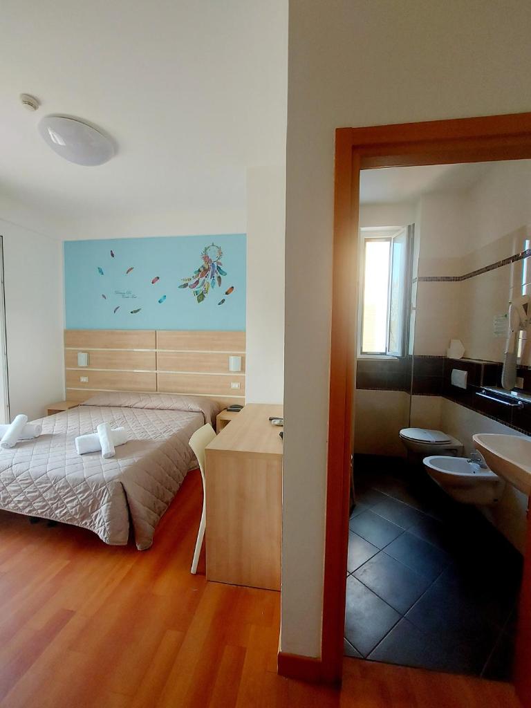 une chambre avec un lit et une salle de bain avec un lavabo dans l'établissement Hotel Monica, à Rimini