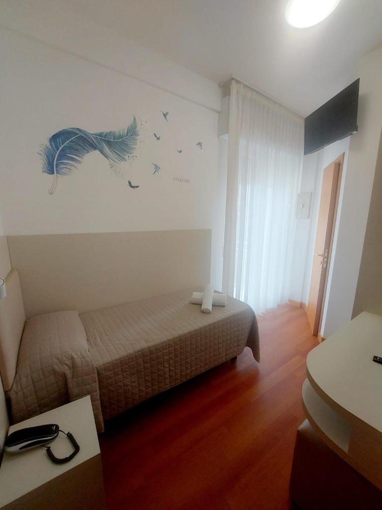 - une chambre avec un lit et un mur orné d'oiseaux dans l'établissement Hotel Monica, à Rimini