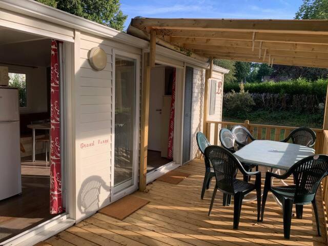 un patio avec une table et des chaises sur un porche dans l'établissement Bungalow climatisé dans un bel écrin de nature, à Saint-Chéron