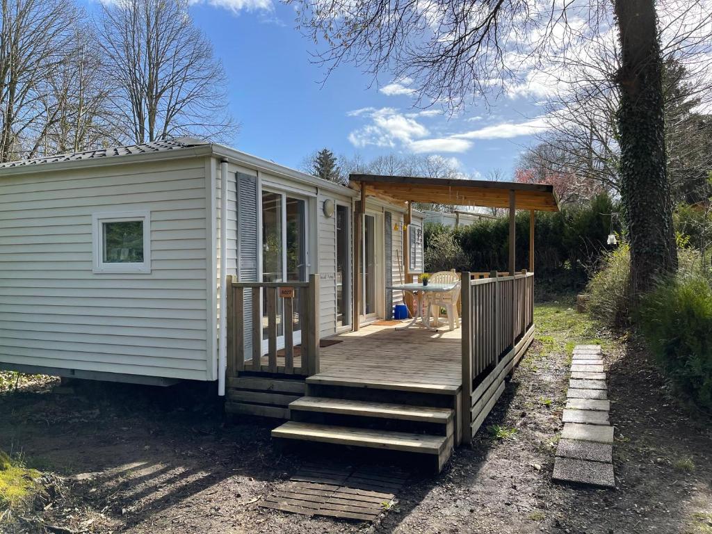 Cette petite maison blanche dispose d'une terrasse couverte et d'une rampe en bois. dans l'établissement Bungalow climatisé dans un bel écrin de nature, à Saint-Chéron